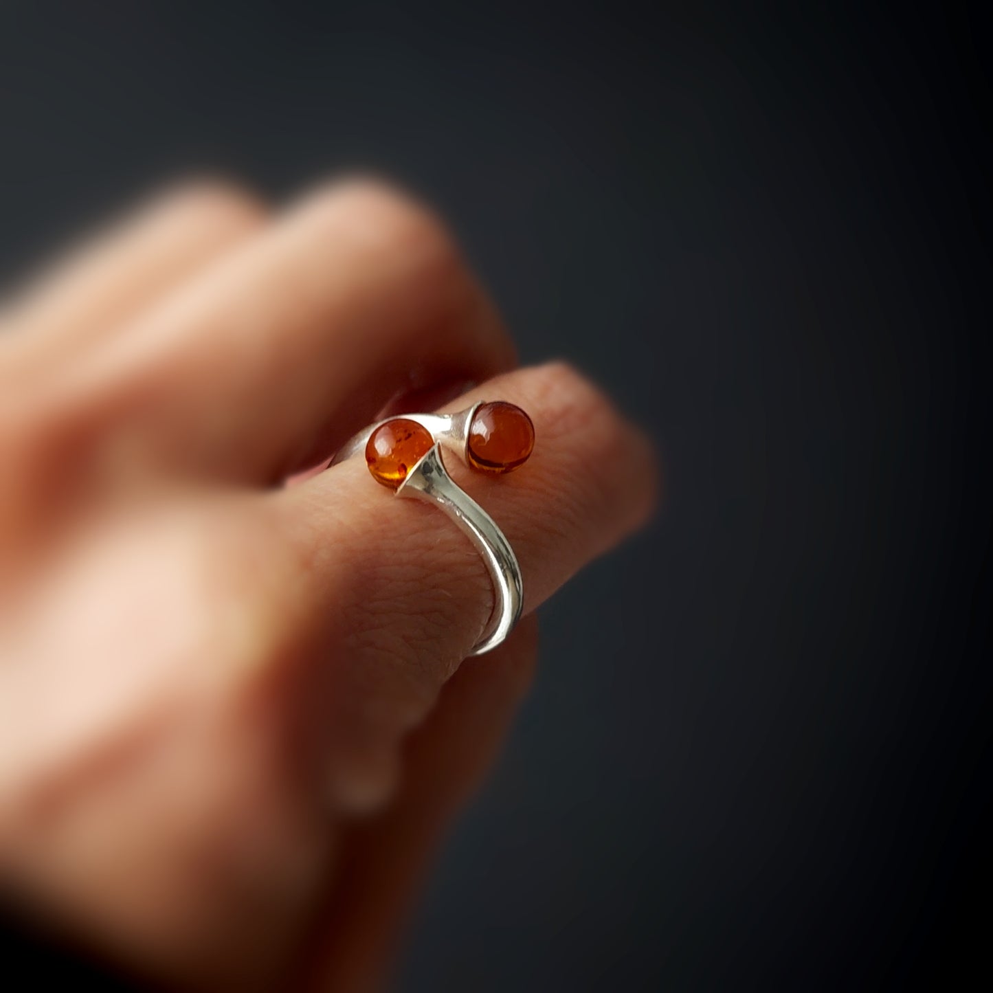 Adjustable sterling silver ring with two round cognac Baltic amber balls, modern open cuff design, minimalist handmade jewelry.