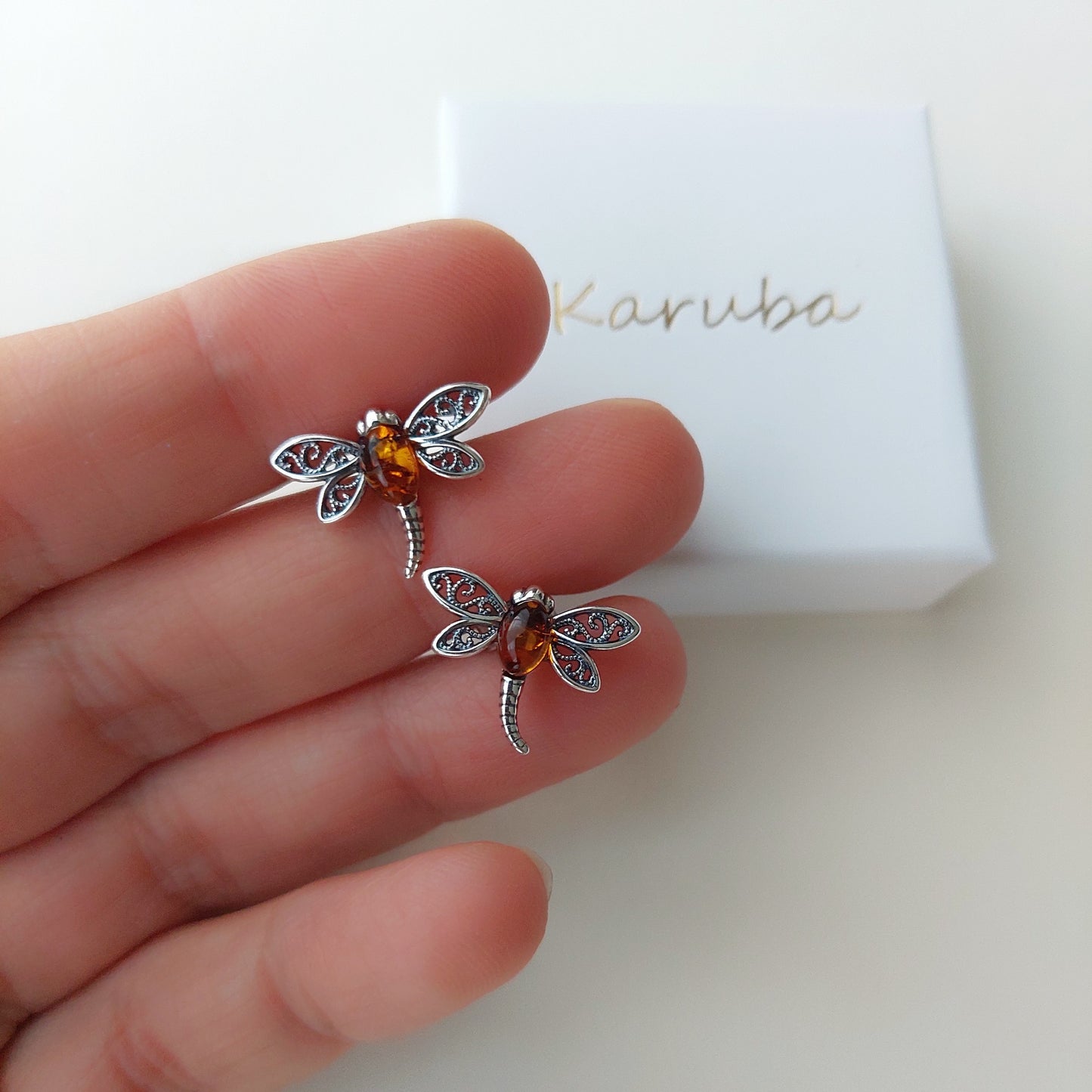 pair of earrings made of silver, adorned with natural amber, inspired by the beauty of nature. These charming stud earrings captivate with their delicate dragonfly design.