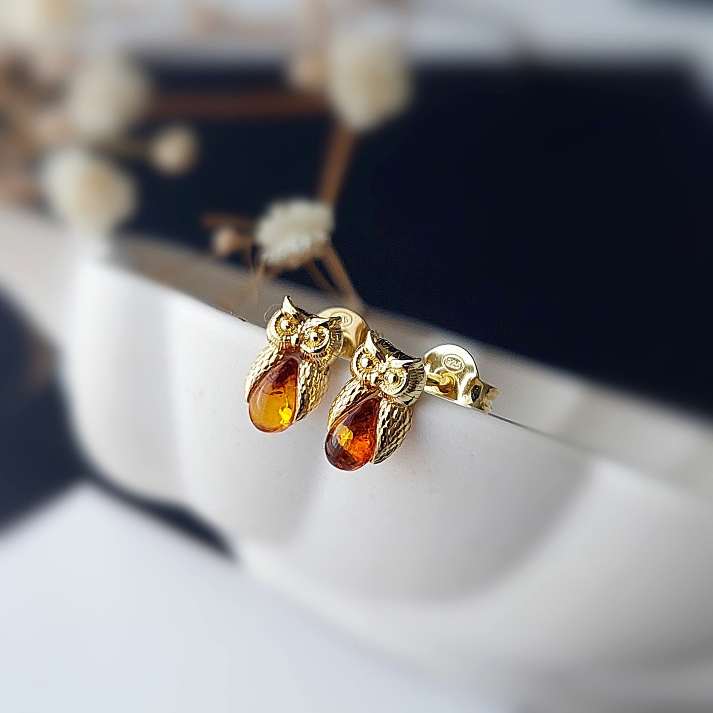 Gold earrings with amber stones on a blurred background