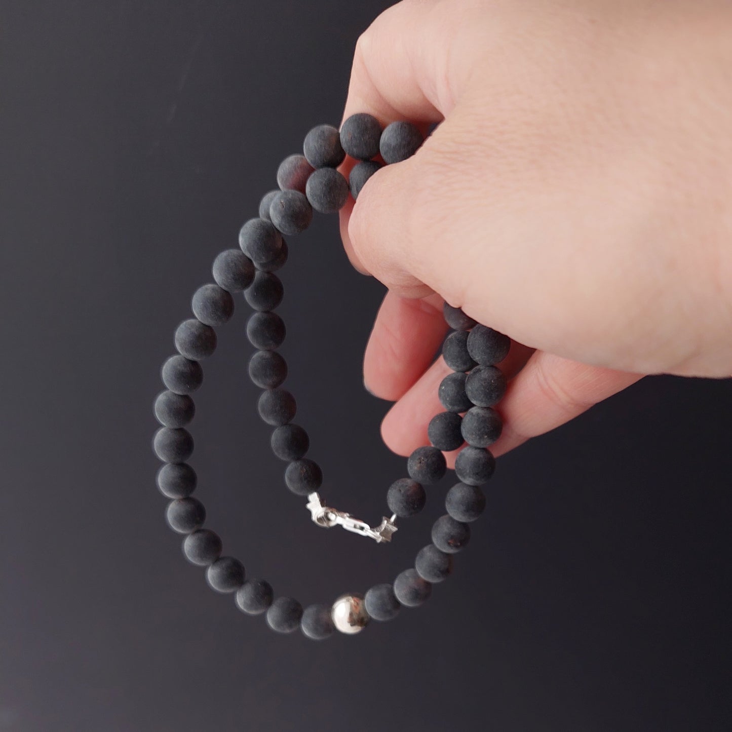 Black matte Baltic amber necklace with central sterling silver bead, elegant and minimalist jewelry piece