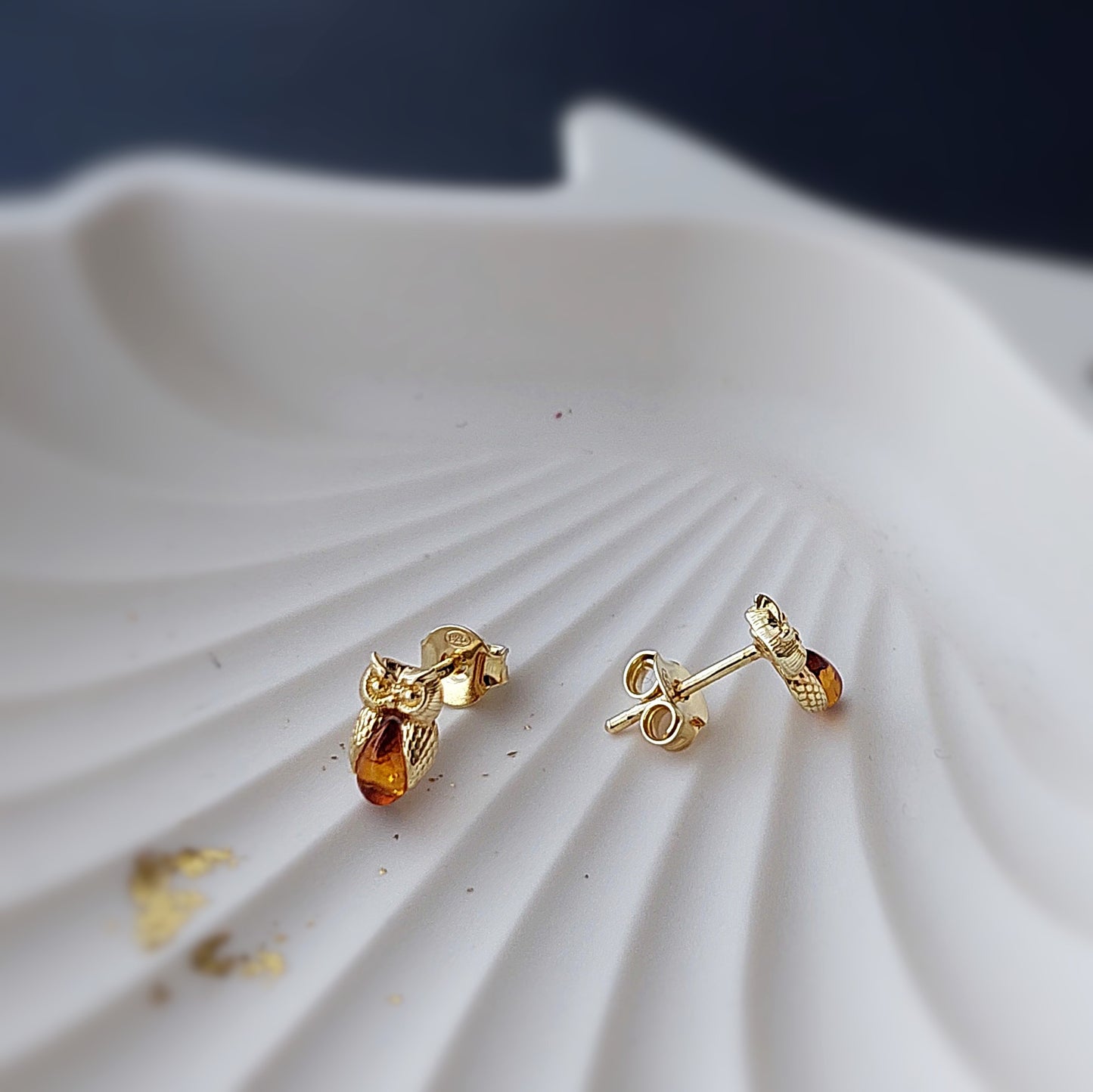 Gold earrings with amber stones on a white shell