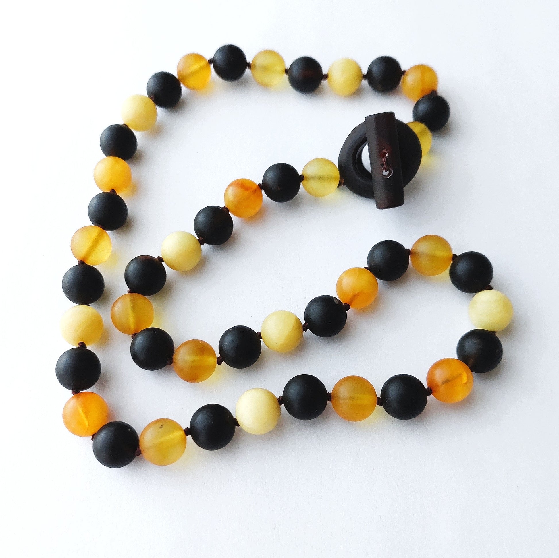 Necklace with black, yellow, and orange beads on a white background