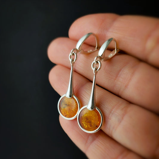Long sterling silver dangle earrings with round cognac Baltic amber – modern minimalist jewelry handmade in Poland